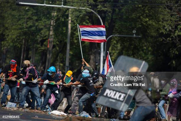 Anti-government protesters remove part of a barricade as they attempt to occupy the government house on December 2, 2013 in Bangkok, Thailand....