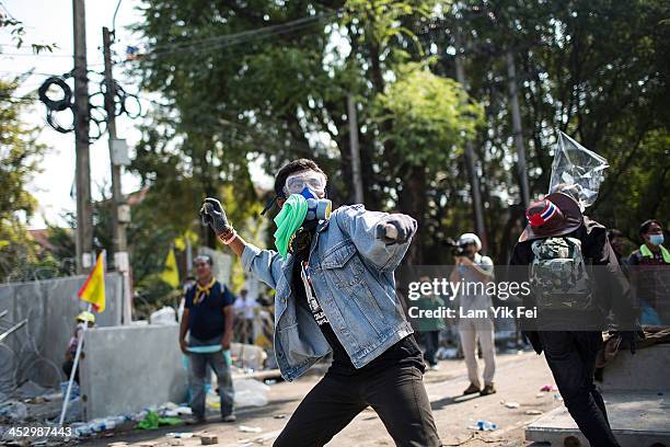 An anti-government protester throws a stone as they attempt to occupy the government houseon December 2, 2013 in Bangkok, Thailand. Anti-government...