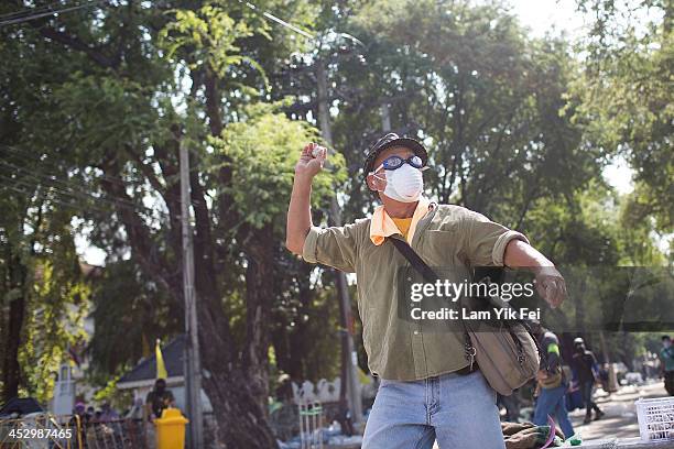 An anti-government protester throws a stone as they attempt to occupy the government houseon December 2, 2013 in Bangkok, Thailand. Anti-government...