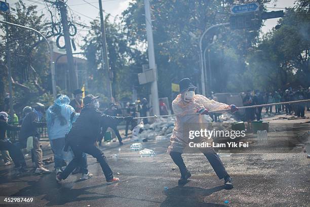 Anti-government protesters remove part of a barricade as they attempt to occupy the government house on December 2, 2013 in Bangkok, Thailand....