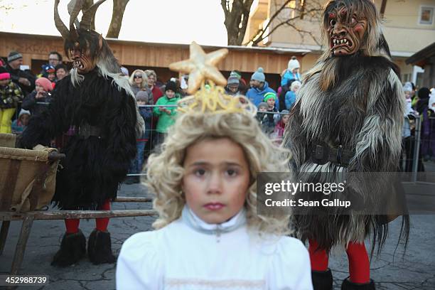 Members of the Haiminger Krampusgruppe dressed as the Krampus creature watch as little girls dressed as angels distribute sweets prior to the annual...