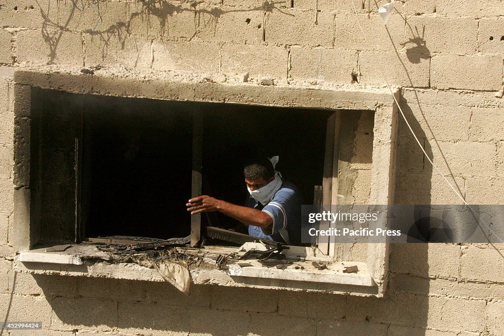 A Palestinian tries to extinguish the fire in his home after...