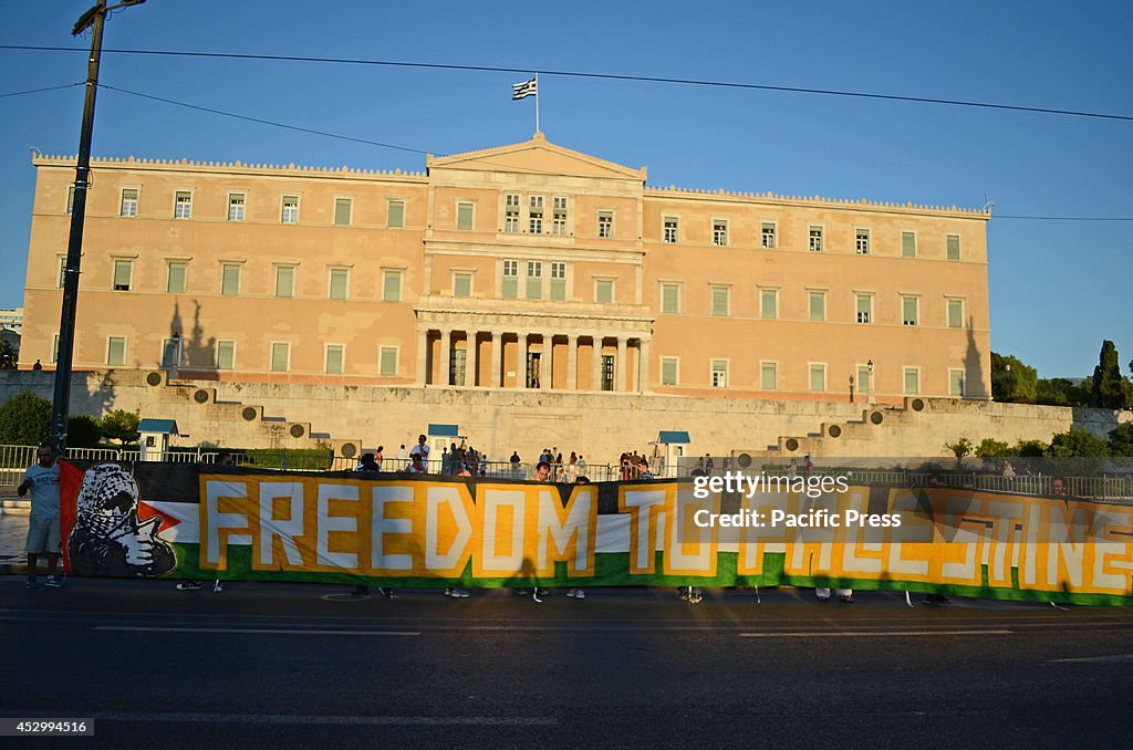 Demonstrators hold a giant banner in front of the Greek...