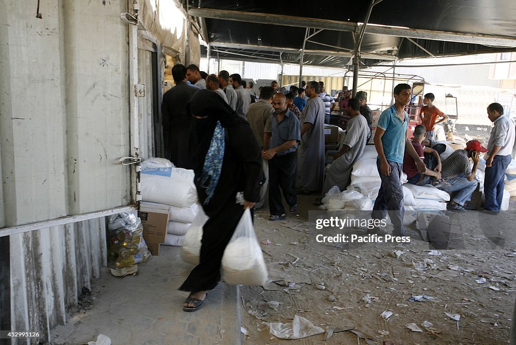 Palestinians receive their monthly food aid at a United...