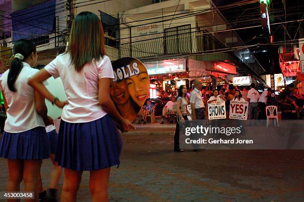 Outside a go-go bar on Walking Street in Pattaya, sexily dressed girls try to entice customers by flashing their welcoming smiles, holding...