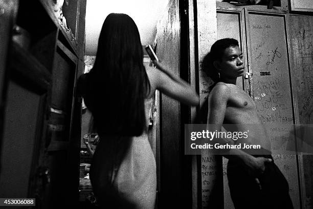 Prostitute brushes her hair in preparation for a night's work, at the primitive living quarters offered by the brothel she works for. A boy stands by...