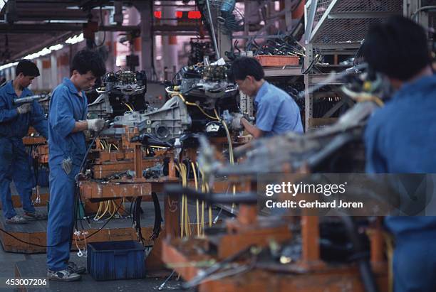 Mechanics work on engines at Shanghai Volkswagen Automotive Company Ltd assembly plant. Here they produce the Santana model for the local market. On...