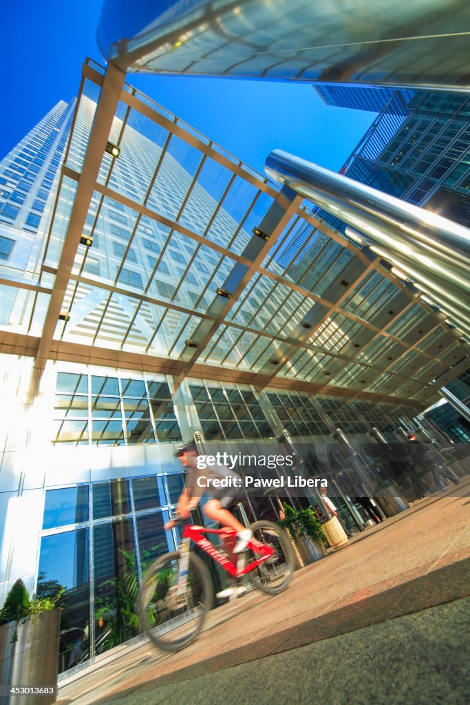 Cyclist passing under One Canada Square Tower aka Canary...