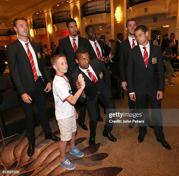 Nani, Jonny Evans, Chris Smalling, David de Gea and Javier "Chicharito" Hernandez of Manchester United pose with a young fan as they arrive in...