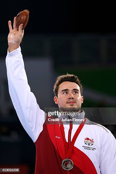 Silver medalist Kristian Thomas of England waves during the medal ceremony for the Men's Horizontal Bar Final at SSE Hydro during day nine of the...