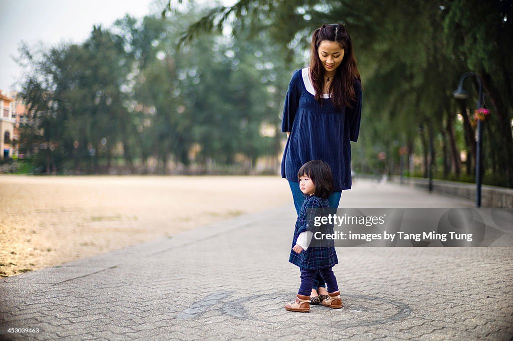 Young mom and toddler girl standing in a pathway