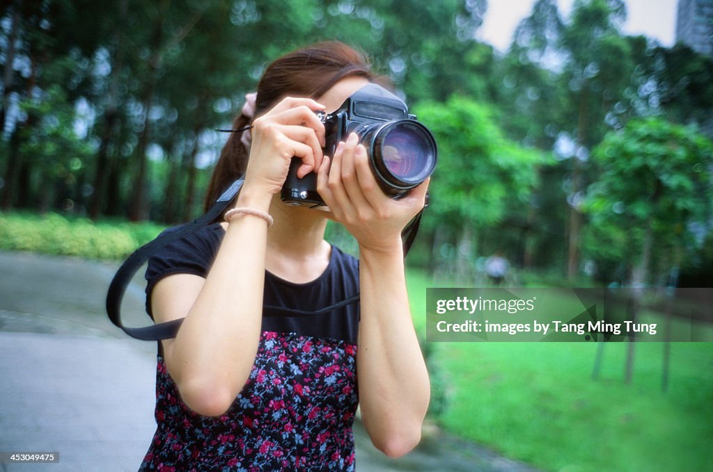 Pretty young lady holding a camera shooting