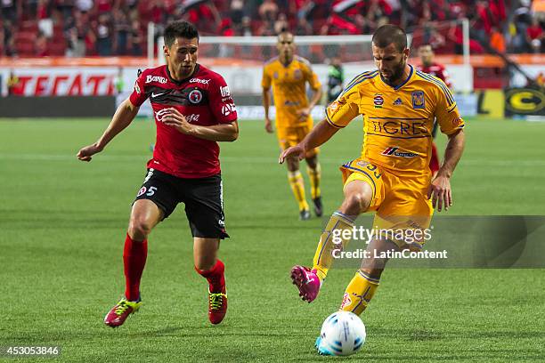 Emanuel Villa of Tigres drives the ball as Elio Castro of Xolos chases him during a match between Tijuana and Tigres UANL as part of 3rd round...