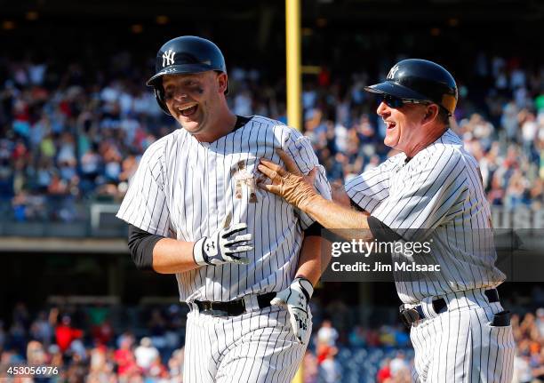 Brian McCann of the New York Yankees celebrates his game winning base hit against the Cincinnati Reds with first base coach Mick Kelleher at Yankee...