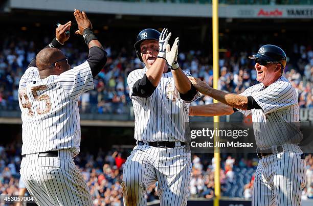 Brian McCann of the New York Yankees celebrates his game winning base hit against the Cincinnati Reds with first base coach Mick Kelleher and Zelous...