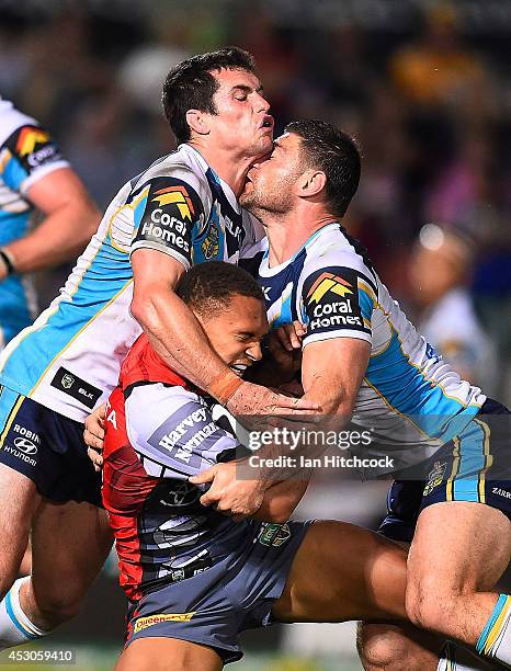 Ray Thompson of the Cowboys is tackled by Daniel Mortimer and Mark Minichiello of the Titans during the round 21 NRL match between the North...