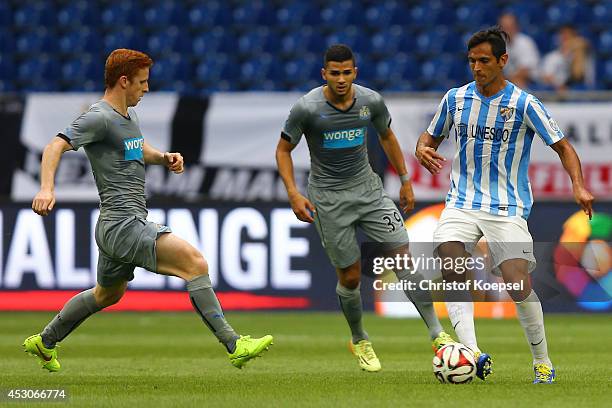 Jack Colback and Mehdi Abeid of Newcastle United challenge Roque Santa Cruz of Malaga during the match between FC Malaga and Newcastle United as part...