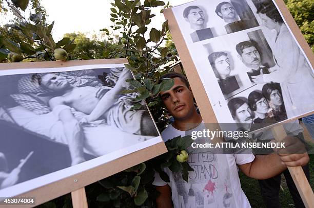 Man holds photos of Roma holocaust victims of the Auschwitz-Birkenau death camp, in Nehru park, in Budapest on August 2, 2014 during the...