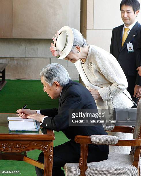 Japanese Emperor Akihito is watched by Empress Michiko as he signs the visitors book during a visit to Raj Ghat, the memorial to Mahatma Gandhi on...