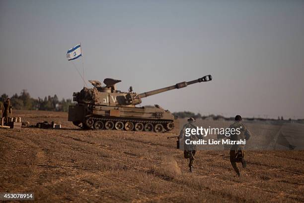 Israeli soldiers run next to a cannon on August 02, 2014 on Israel's border with the Gaza Strip.The Israeli military on Friday cited indications that...