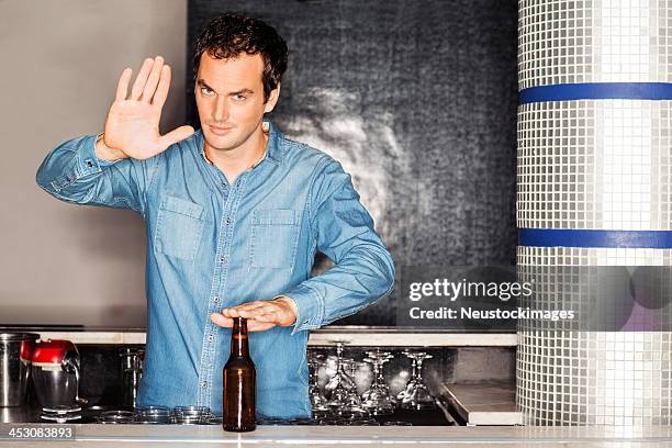 barkeeper mit bierflasche gestikulieren stoppschild an der - alkohol verzicht stock-fotos und bilder