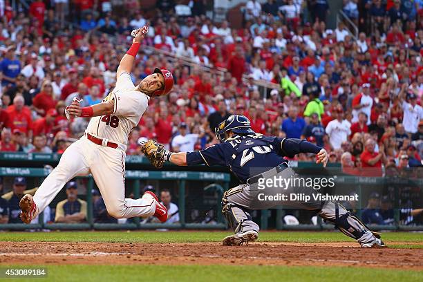Tony Cruz of the St. Louis Cardinals avoids being tagged out by Jonathan Lucroy of the Milwaukee Brewers to score a run in the fourth inning at Busch...