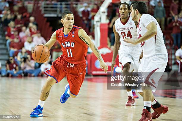 Nic Moore of the SMU Mustangs dribbles down the court while being defended by Kikko Haydar of the Arkansas Razorbacks at Bud Walton Arena on November...