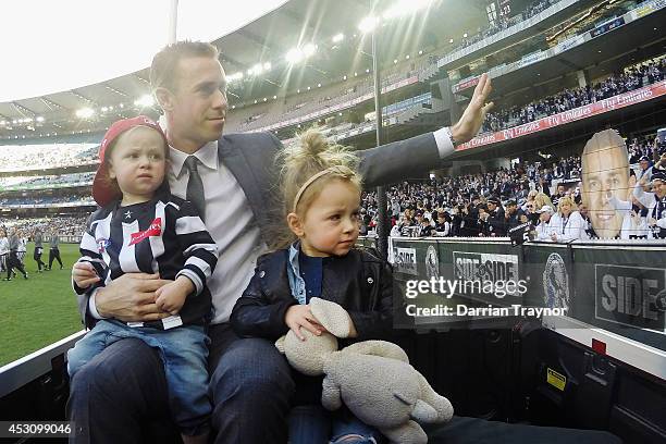 Former Magpies captain Nick Maxwell, who recently retired, does a lap on honour with his children before the round 19 AFL match between the...