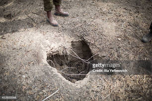 An Israeli soldier checks a hole in the ground while looking for signs of a tunnel from Gaza to Israel on August 3, 2014 near the border with Gaza,...