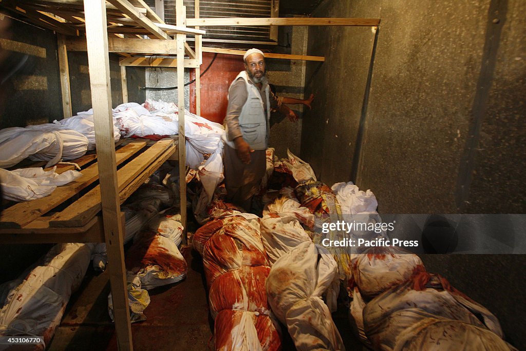 Palestinian relatives stand among bodies in a storage...