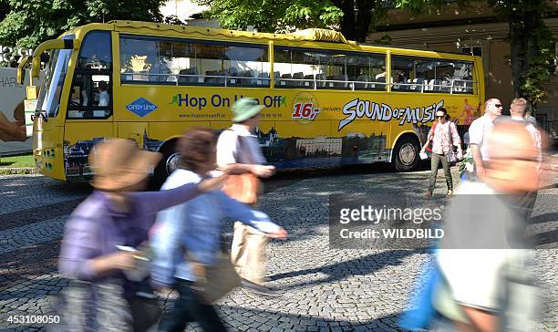 Tourist pass by in front of a bus with the 'Sound of Music' logo at the Mirabell Place in Salzburg, Austria, on August 1, 2014. Every year nearly...