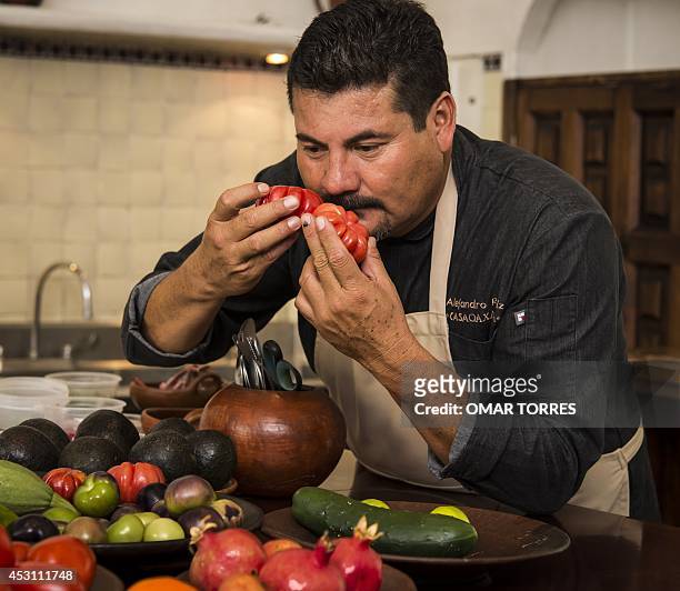 Alejandro Ruiz, chef of "Casa Oaxaca" restaurant, smells red tomatoes in his kitchen, on July 29, 2014 in Oaxaca, Mexico. Ruiz said that aware that...