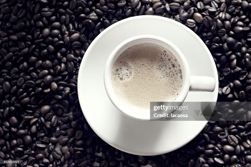 White coffee cup in middle of coffee beans