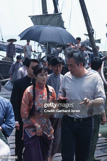 Chinese movie director Chen Kaige gives instructions to actress Gong Li during the filming of 'Temptress Moon'. Actor Leslie Cheung Kwok Wing walks...