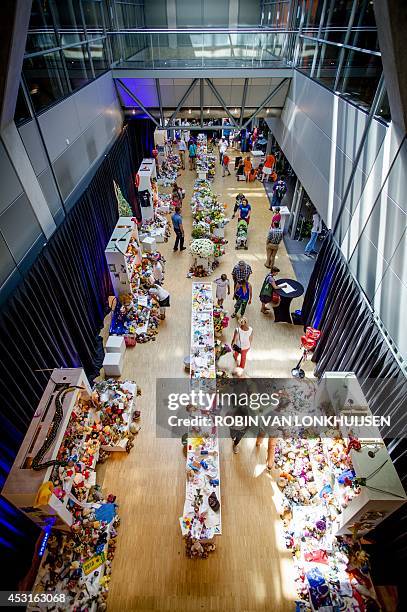 People look at flowers and teddybears brought in a memorial space at the Schiphol Airport in Amsterdam on August 4, 2014 after they were left outside...