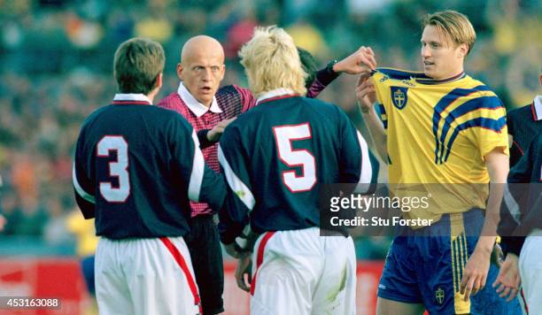 Referee Pierluigi Collina points out the ripped shirt of Sweden striker Kennet Andersson to Scotland defender Colin Hendry during a World Cup...