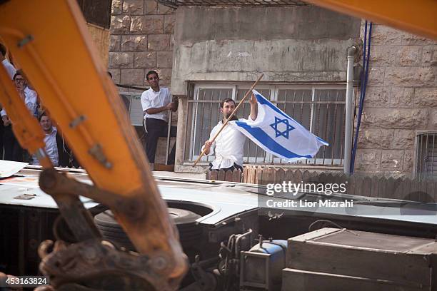 An Ultra Orthodox Jewish man holds an Israeli flag at the scene after a Palestinian man rammed an excavator into a bus on August 04, 2014 in...