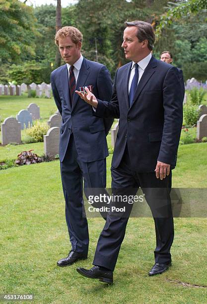 Prince Harry walks with Prime Minister David Cameron past war graves at St Symphorien Military Cemetery on August 4, 2014 in Mons, Belgium. Monday...