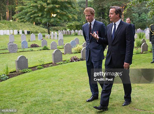 Prince Harry walks with Prime Minister David Cameron past war graves at St Symphorien Military Cemetery on August 4, 2014 in Mons, Belgium. Monday...