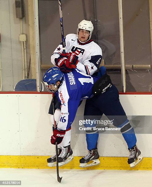 Aleksi Saarela of Team Finland hits Jack Dougherty of USA White during the 2014 USA Hockey Junior Evaluation Camp at Lake Placid Olympic Center on...