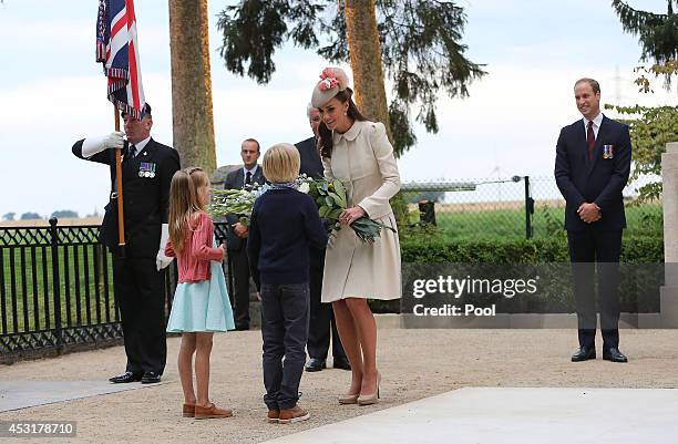 Catherine, Duchess of Cambridge receives a bunch of flowers to lay during a ceremony at St Symphorien Military Cemetery on August 4, 2014 in Mons,...