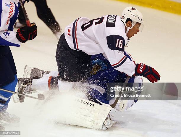 Keegan Iverson of USA White takes a charging penalty on goaltender Juuse Saros of Team Finland during the 2014 USA Hockey Junior Evaluation Camp at...