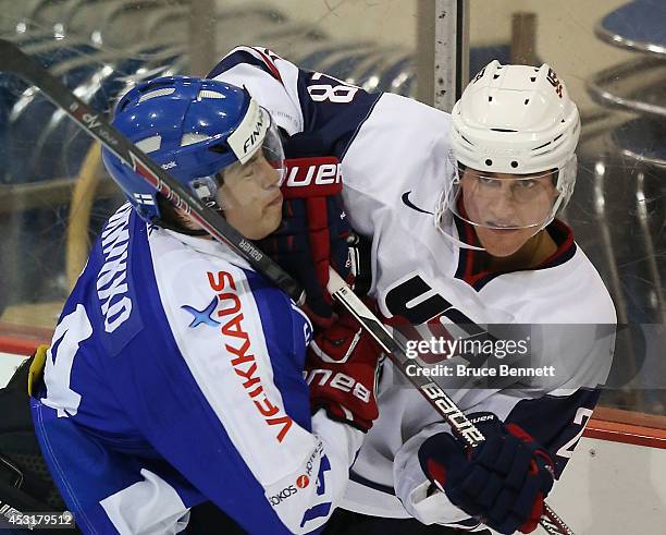 Clint Lewis of USA White is checked into the boards by Juho Lammikko of Team Finland during the 2014 USA Hockey Junior Evaluation Camp at the Lake...