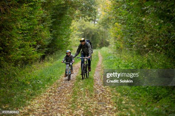 father and son cycling together in nature - kids on bikes stockfoto's en -beelden