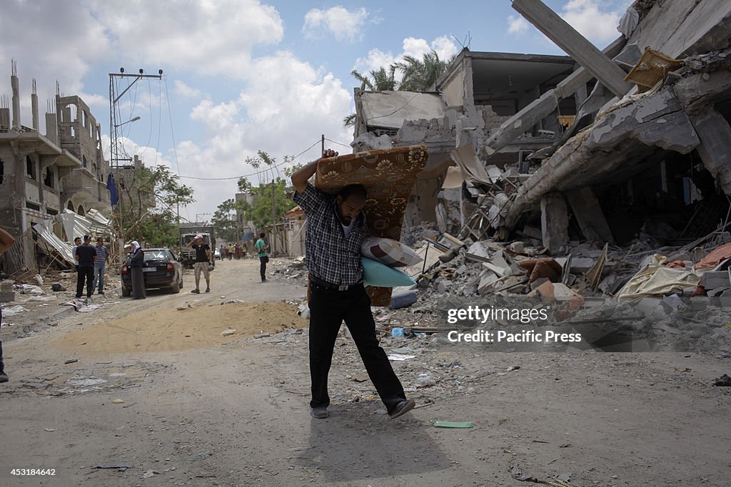 A Palestinian gathering what is left of his home destroyed...