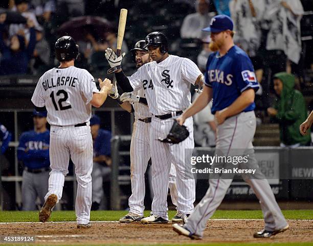 Dayan Viciedo and Adam Eaton of the Chicago White Sox high-five teammate Conor Gillaspie at home plate after Gillaspie and Viciedo scored on an RBI...