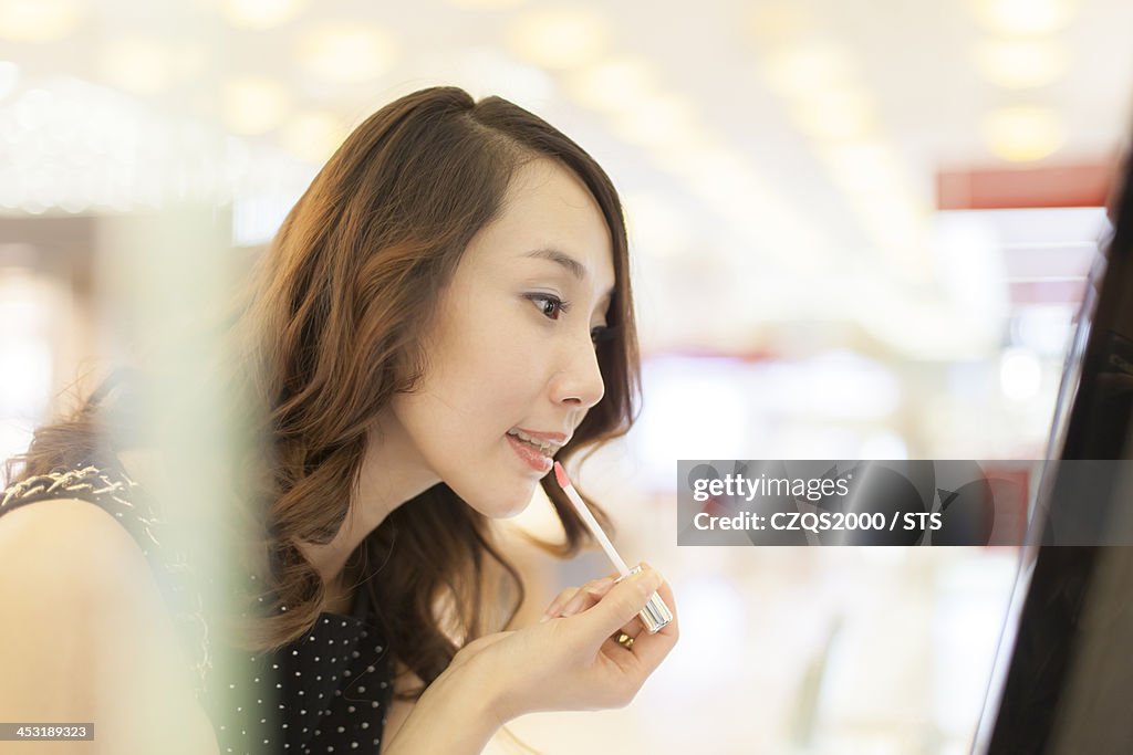 Young woman choosing cosmetics in shopping mall