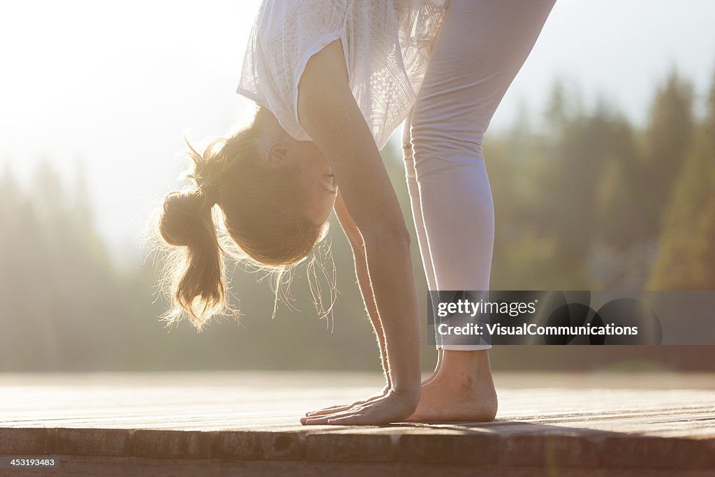 Woman practising yoga by the lake.