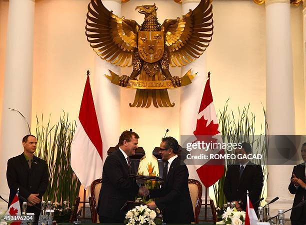Canadian Foreign Minister John Baird and his Indonesian counterpart Marty Natalegawa exchange documents after the signing of Plan of Action towards...