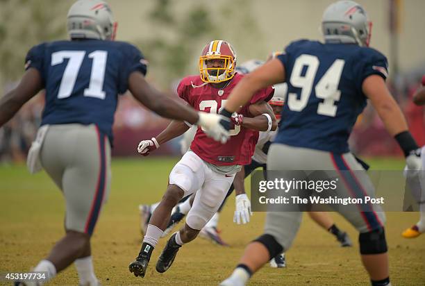 Washington defensive back Akeem Davis prepares to collide with New England's Zach Moore , left, and Chris Jones during special team drills during day...